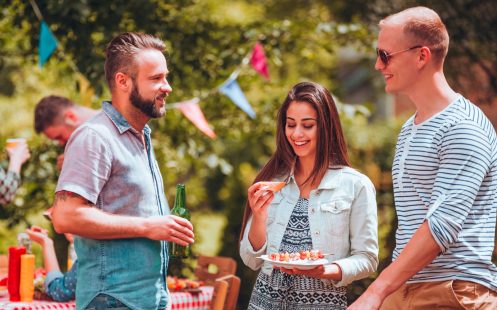 Student friends talking over a grill during a garden party in summer