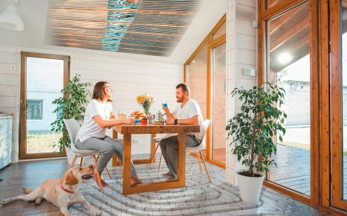 Young couple having a breakfast sitting with dog in the dining room in the wooden country house